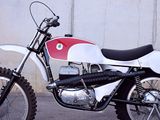 a white and red dirt bike parked in front of a concrete wall