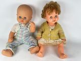 two dolls sitting next to each other on a white surface