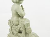 figurine of a boy sitting on a stool with his hands on his knees