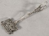 a silver spoon with a handle on a white surface