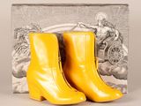 des bottines en cuir jaune avec une boîte de livres en arrière-plan