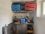 a small kitchen with a sink and several crates on the wall