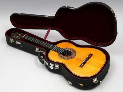 une guitare dans un étui, posée sur une surface blanche