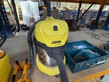un aspirateur jaune et noir posé sur une étagère dans un garage