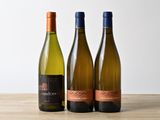 trois bouteilles de vin sont alignées sur une table en bois