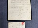une vieille lettre et une enveloppe, posées sur un tissu bleu, avec une enveloppe rouge par-dessus