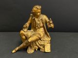 an antique bronze figurine of a man sitting on a chair