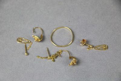 three pairs of gold rings and a pair of earrings on a table