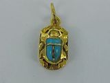 a close up of a gold pendant with a blue stone in the center