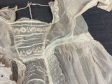 a white dress on a bed with a basket of flowers