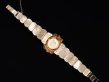 a gold and mother of pearl watch on a chain