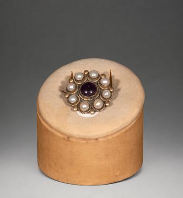gold ring with amethorate and pearls on a wooden box