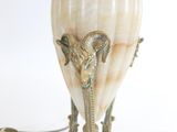 un vase blanc orné d'une tête de bélier, posé sur une table