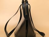 black leather handbag with a zippered strap on a beige background