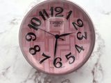 a pink clock sitting on top of a marble table