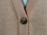 the back of a pink cardigan sweater with a button on it