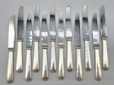 six silverplated knives and six knives on a white surface