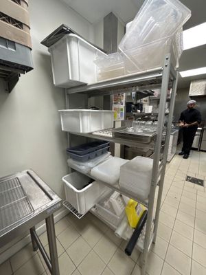 un homme debout dans une cuisine, à côté d'une étagère