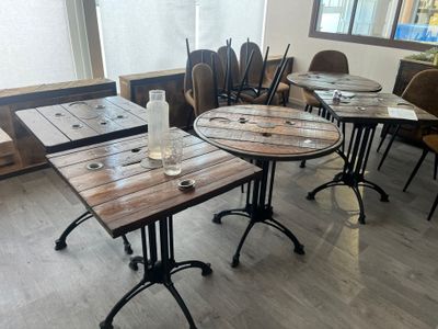 plusieurs tables et chaises dans une pièce dotée d'une fenêtre, avec une table sur laquelle est posé un verre