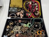 une boîte noire remplie de bijoux variés posée sur une surface blanche