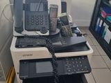 une pile de téléphones et une imprimante dans une pièce