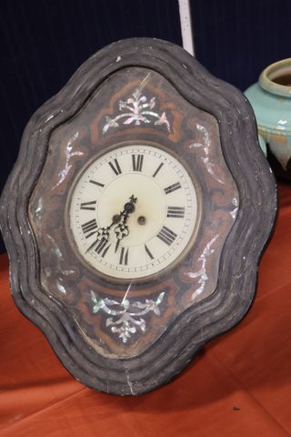 Pendule œil de bœuf cadre stuc noirci décor de nacre. 