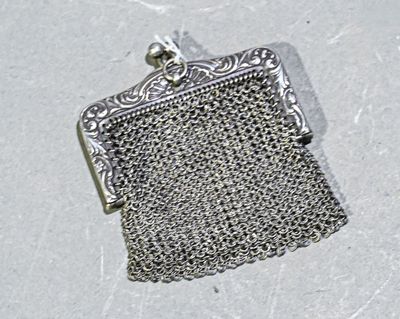 un porte-monnaie en métal argenté, entouré d'une chaîne, posé sur un fond blanc