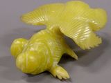 a yellow figurine of a fish on a gray surface