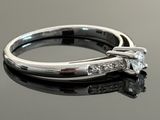 a close up of a diamond engagement ring on a reflective surface