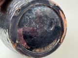 a close up of a black vase with rust on it