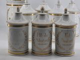 several white and gold canisters are lined up on a white surface
