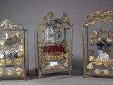 Trois horloges anciennes sont exposées sur une table recouverte d'un tissu rouge