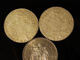 three gold coins sitting on top of each other on a black surface