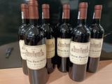 six bouteilles de vin rouge sont alignées sur un comptoir