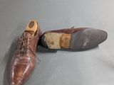 pair of men ' s brown leather shoes on a gray surface