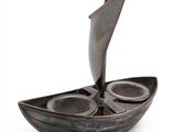 a small boat with two cups in it on a white surface