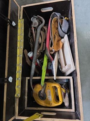 une caisse en bois posée par terre, contenant des outils