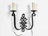 pair of wrought iron wall sconces with candle holders on a white background