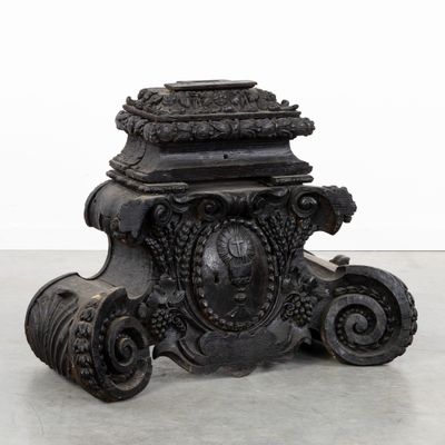 un vase noir orné d'un motif, posé par terre