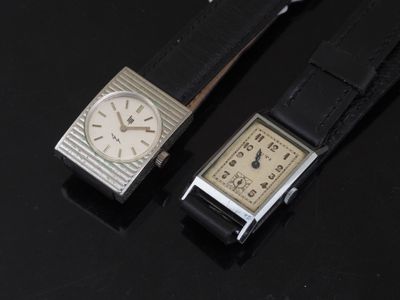 two watches sitting next to each other on a black surface