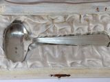 une cuillère en argent et un repose-cuillère dans une boîte