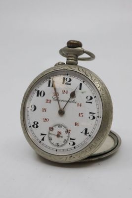 a silver pocket watch sitting on top of a white table