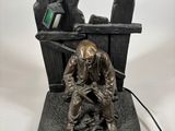 statue of a man sitting on a bench with a laptop on his lap