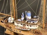 a model of a wooden ship with a white sail