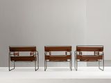 three brown leather chairs sitting on top of a white platform