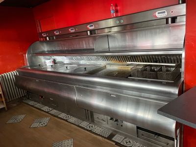 une grande cuisine professionnelle équipée d'appareils électroménagers en inox et aux murs rouges