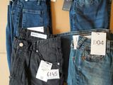trois paires de jeans pour homme posées sur une boîte en carton