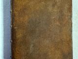 un vieux livre posé sur une table recouverte d'un tissu blanc