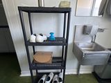une étagère noire sur laquelle sont posées des chaussures, dans une petite pièce