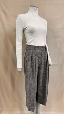 Le mannequin porte un haut blanc et un pantalon gris.